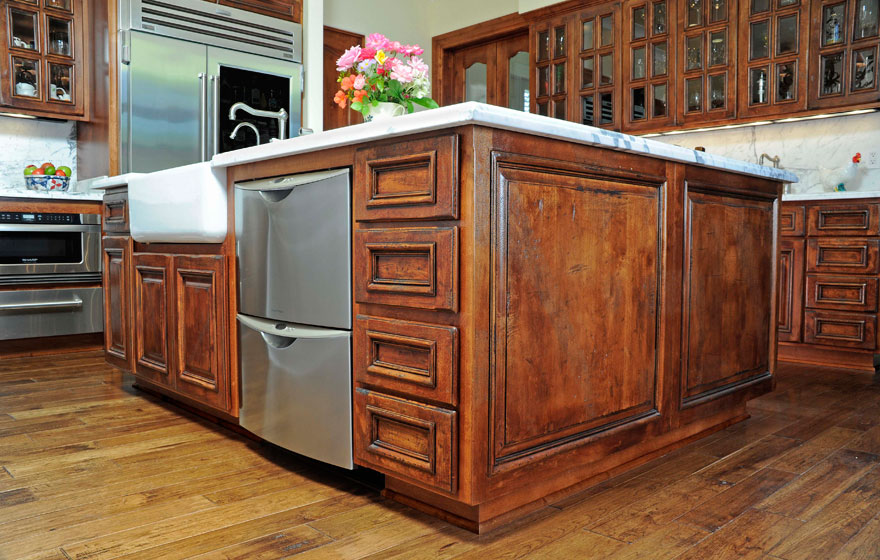 French Lite upper cabinets dazzle this kitchen where the rustic hand-distressed cabinetry contrasts the elegant marble countertops.